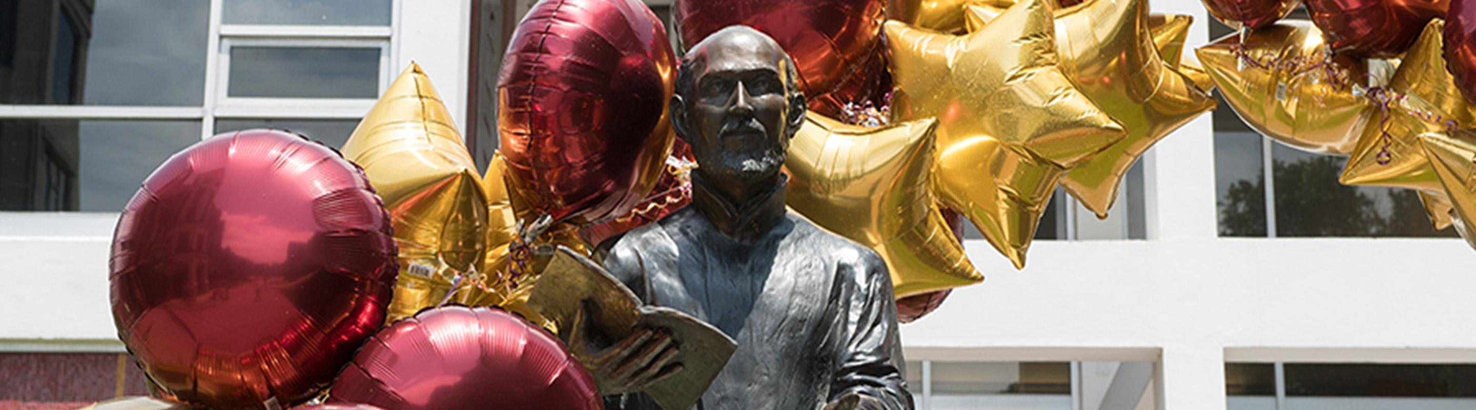 STraight on shot of Ignatius statue with maroon and gold balloons